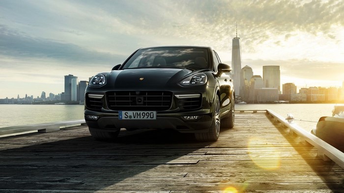Black Porsche Cayenne on a wooden pier with city skyline