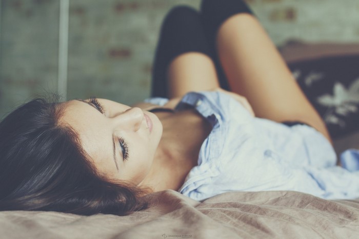 Woman lying on a bed wearing a blue shirt