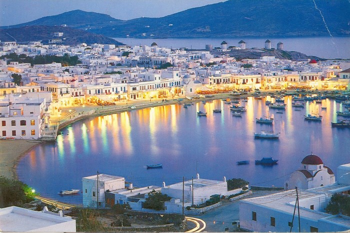 Mykonos Town harbor at dusk with windmills in the background
