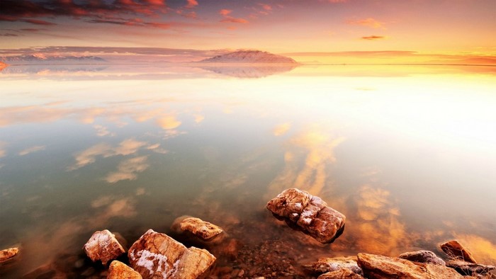 Sunset reflection over water with rocks and mountains