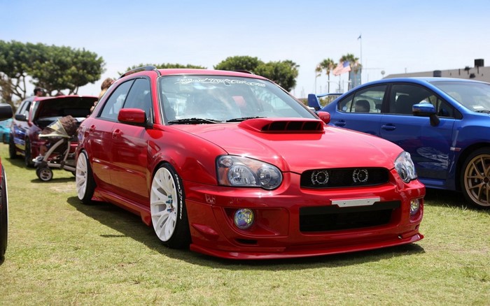 Red Subaru Impreza WRX STi hatchback with white wheels