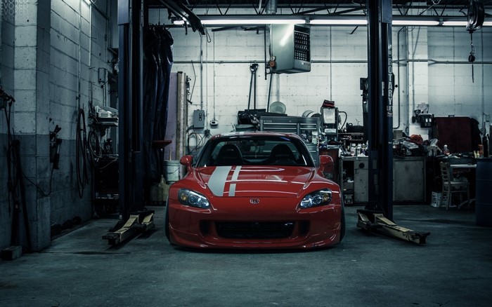 Red Honda S2000 in a garage with car lift