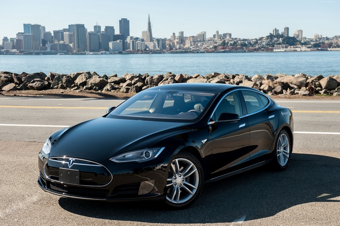 Black Tesla Model S parked by the water with San Francisco skyline