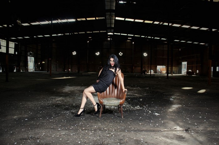 Woman in black dress sitting in an abandoned warehouse