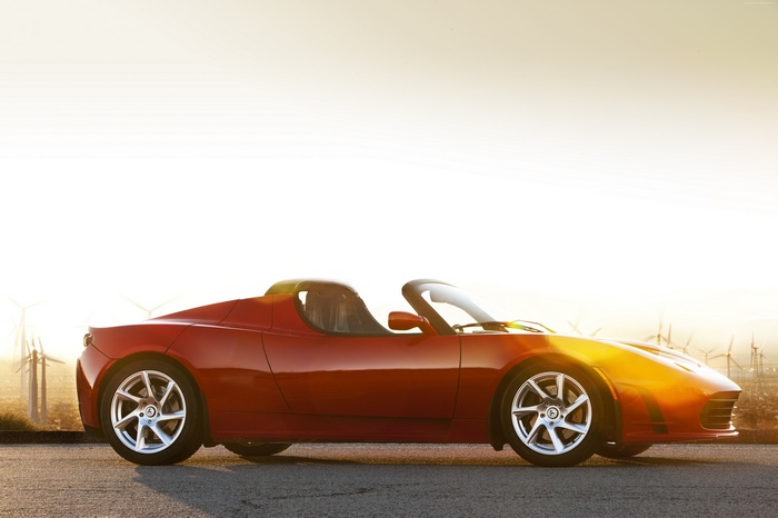 Red Tesla Roadster sports car with wind turbines