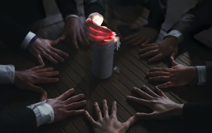 Hands around a candle during a séance
