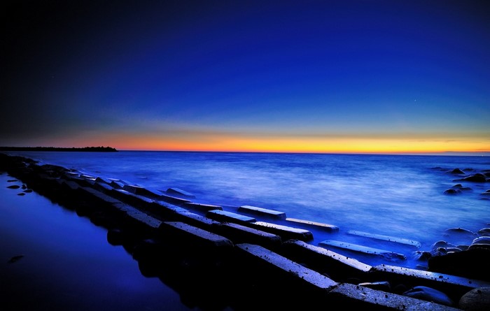 Sunset over the ocean with concrete breakwaters