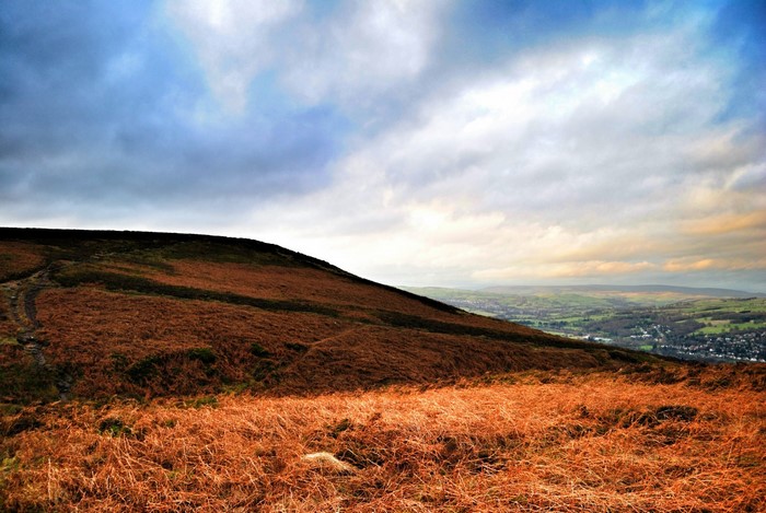 Brown hillside overlooking a valley under a cloudy sky