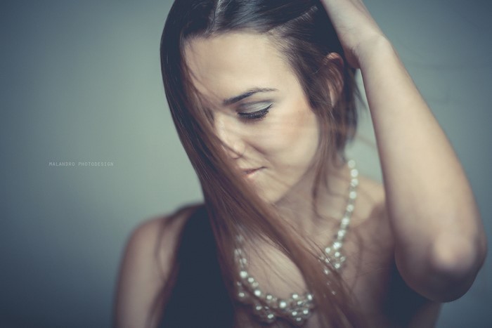 Woman with long brown hair and pearl necklace