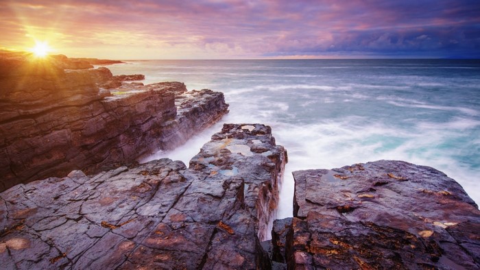 Rocky coast at sunset with waves crashing