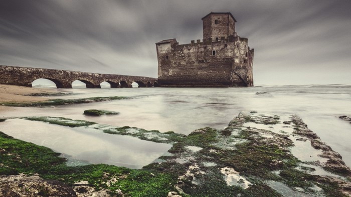 Stone castle and arched bridge on the coast
