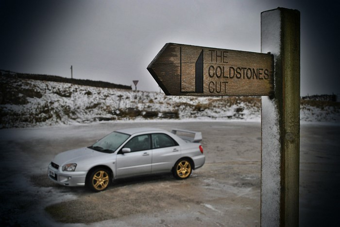 Silver Subaru Impreza with a directional sign in the snow