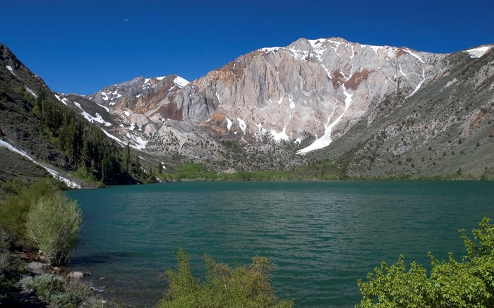 Turquoise lake and snow-capped mountains under a blue sky