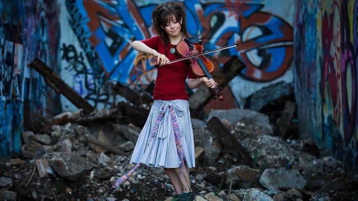 Woman playing violin in front of graffiti wall