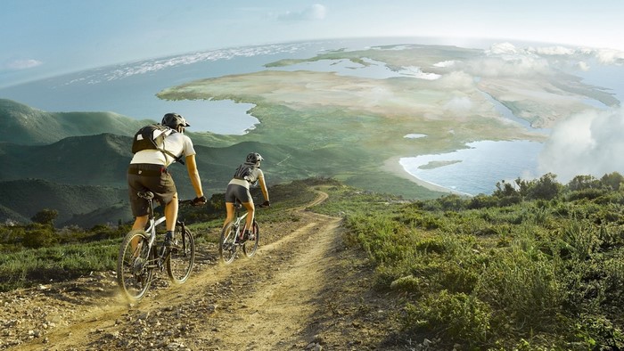 Two people mountain biking on a dirt road with a panoramic view