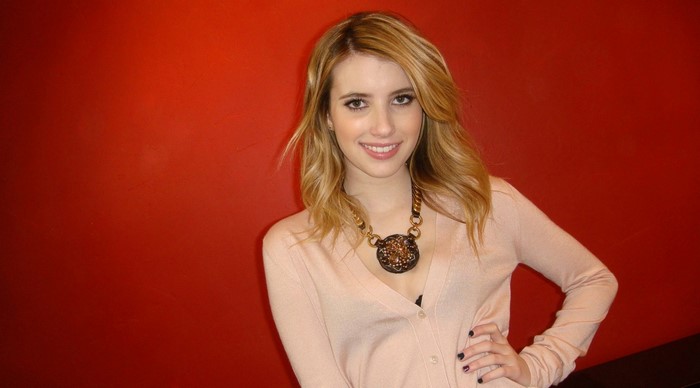 Emma Roberts posing in front of a red wall