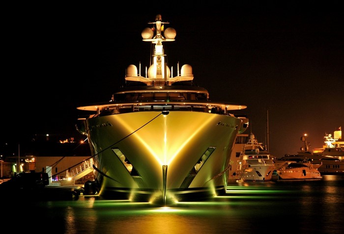 Luxury yachts docked at night with bright lighting