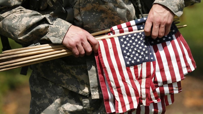 Soldier holding American flags and wooden sticks
