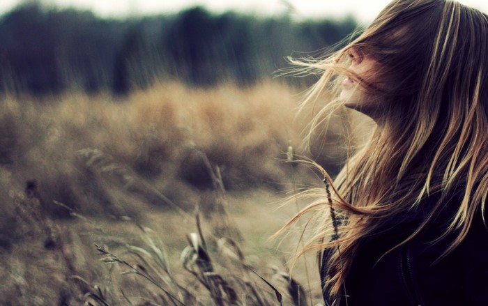 Woman with hair blowing in the wind in a field
