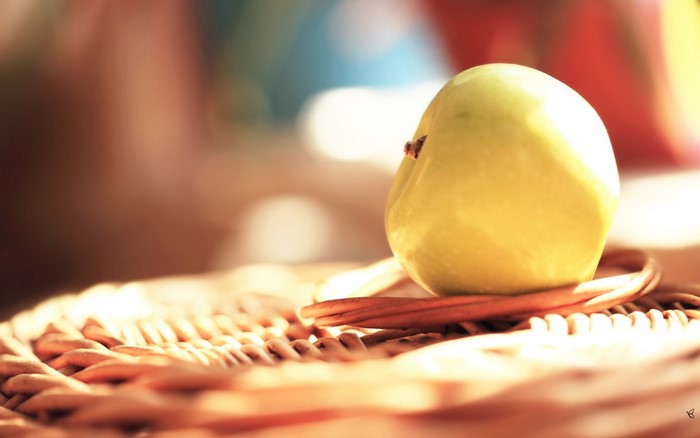 Yellow apple on a woven surface