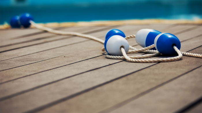Blue and white buoys on a rope on a wooden deck
