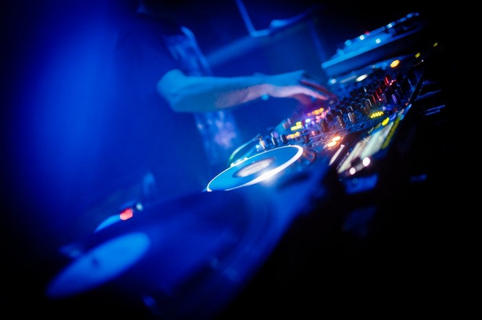 DJ mixing music on turntables with blue lighting