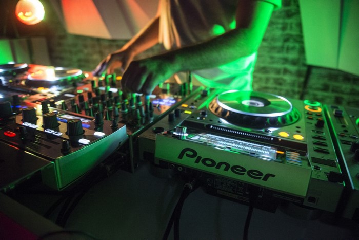 DJ mixing music on Pioneer turntables with green lighting