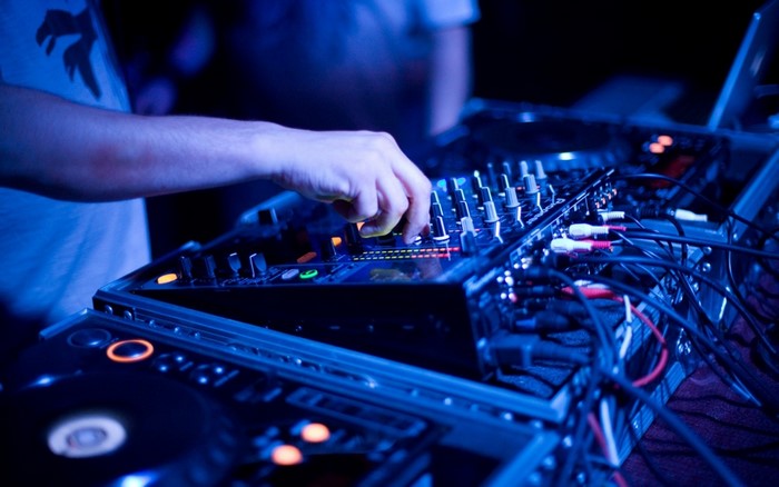 DJ mixing music on a console with cables