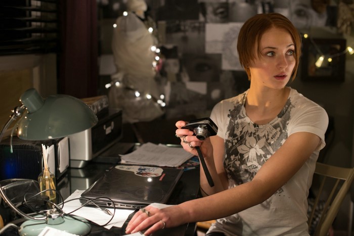 Sophie Turner holding a camera at a desk