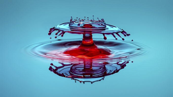 Red and blue water drops colliding and splashing