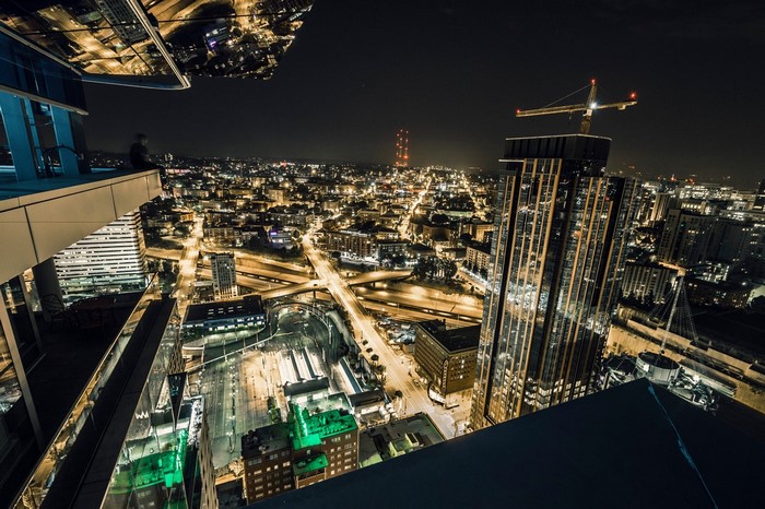Person on skyscraper overlooking city at night