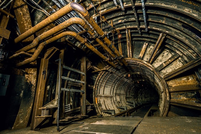 Abandoned industrial tunnel with pipes and metal structures