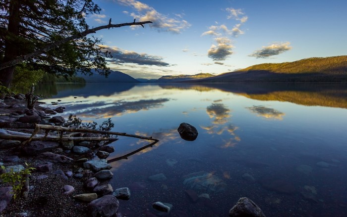 Calm lake with reflection of mountains and clouds at sunrise
