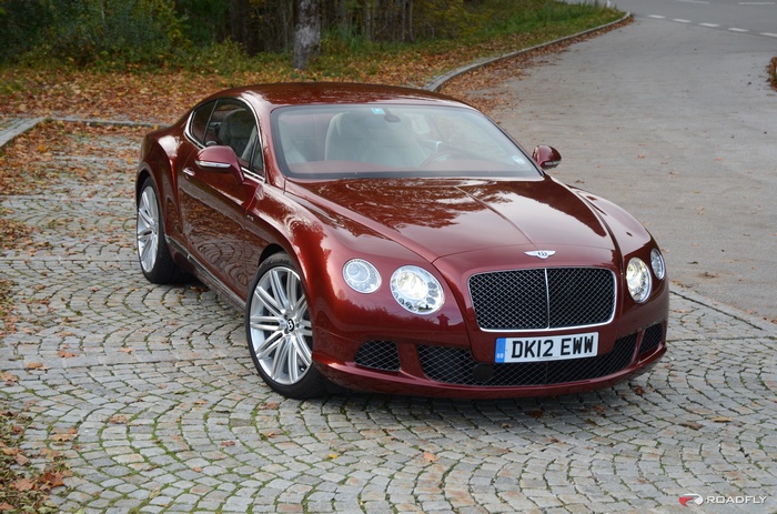 Red Bentley Continental GT parked on cobblestone