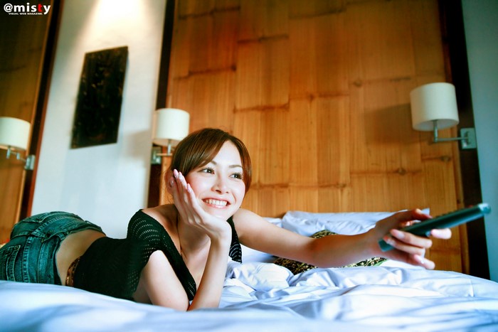 Woman in jeans and black top holding remote