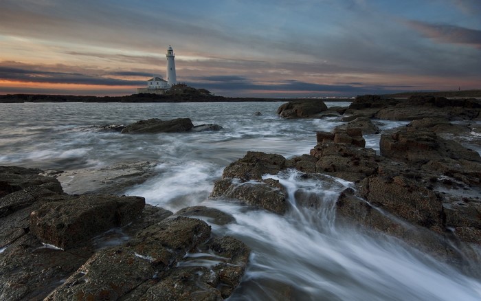 Lighthouse at Dusk Over Rocky Shoreline