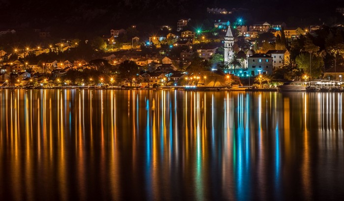 Town lights reflecting on water at night in Montenegro