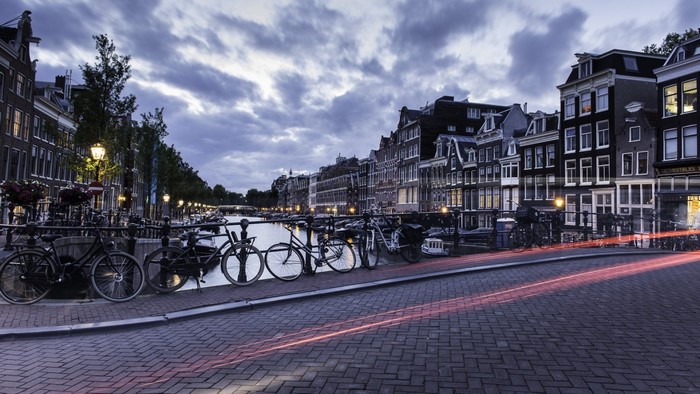 Amsterdam canal with bicycles and light trails at dusk
