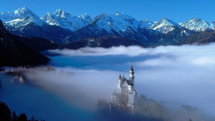 Neuschwanstein Castle in the Alps with Fog and Snow-Capped Mountains