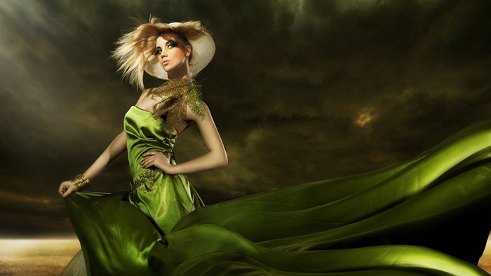 Woman in green dress and hat with dramatic lighting