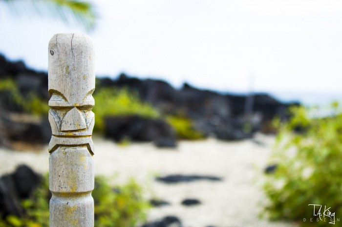 Wooden Tiki statue on a beach with lava rocks
