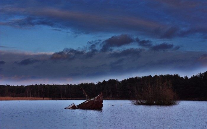Shipwreck in a lake at dusk with dark clouds