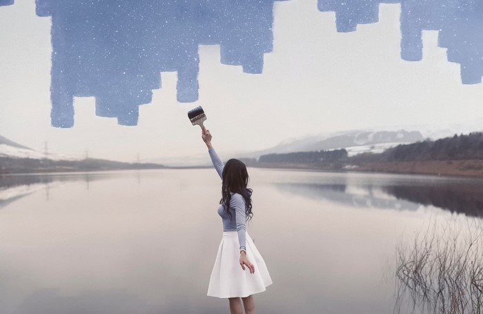 Woman painting a city skyline over a lake