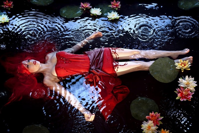 Woman in Red Dress Floating in Water with Lilies