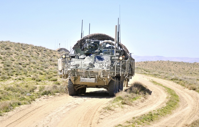 U.S. Army Stryker ICV drives on a dirt road in a desert
