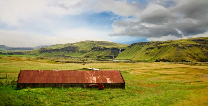 Barn in a green valley with waterfalls in Iceland