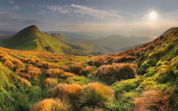 Mountain landscape with rolling hills and sun