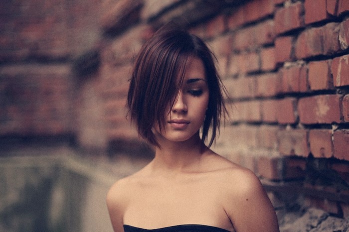 Woman with short brown hair against a brick wall
