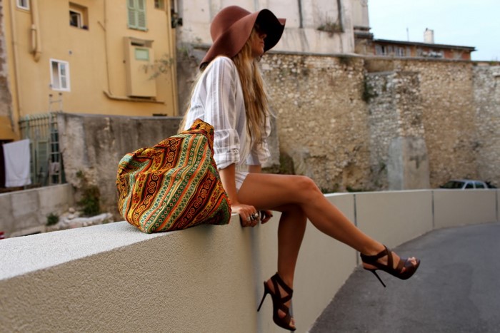 Woman in hat and patterned bag sitting outdoors