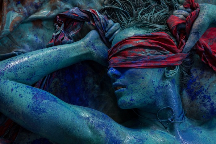 Woman covered in blue body paint with red blindfold